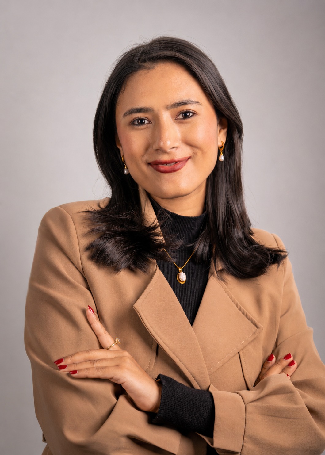 Priyanka Shrestha in a camel blazer, smiling with folded arms
